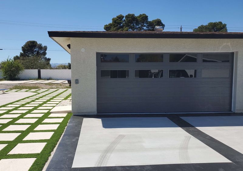 A modern garage door with a row of windows on a single-story desert home